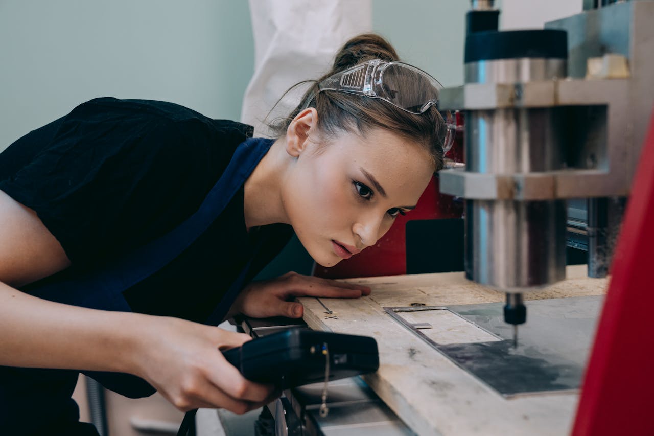The Art of Drawing Readers In: Your attractive post title goes here Woman closely inspecting machinery in a workshop wearing protective goggles.